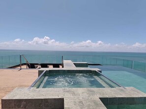 A infinity pool with a clear view of the ocean, a glass railing, and a tiled deck. - New Time Building - Apartment 1016, Beira Mar, Pajuçara - Maceió/AL (Maceió)