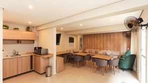 Una cocina moderna con armarios de madera, un comedor con mesa y sillas de madera, y un sillón verde.