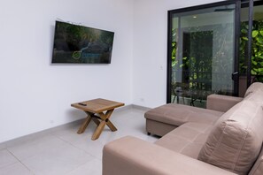 Ein modernes Wohnzimmer mit einem beigefarbenen Sofa, einem Holztisch und einem flachbildfernseher, der an der Wand montiert ist.