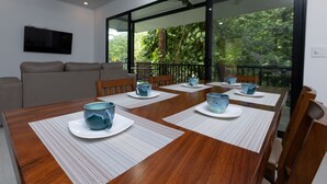Een eethoek met een houten tafel, witte placemats en blauwe keramische kopjes.