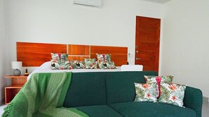 Een kamer met een groene bank, een houten hoofdbord en een bed met bloemenkussens.