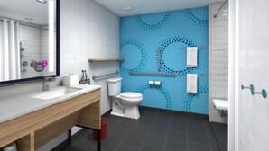 Een moderne badkamer met een wit wastafelmeubel, toilet en douchegedeelte. Er zijn grepen en een handdoekhouder aan de muur bevestigd.
