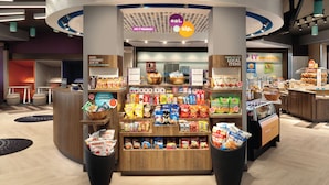 Een markt, dag en nacht geopend, met diverse snacks en dranken, zoals chips en flessenwater.