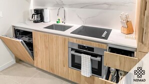 Eine moderne Küche mit Holzausstattung, einem doppelten Waschbecken, einer Kaffeemaschine und einem Geschirrspüler.