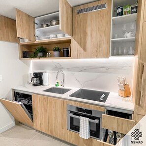 Eine moderne Küche mit Holzausstattung, einem doppelten Waschbecken, einer Kaffeemaschine und einem Geschirrspüler.