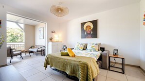 Un dormitorio con cama, una silla, una mesita y un balcón.