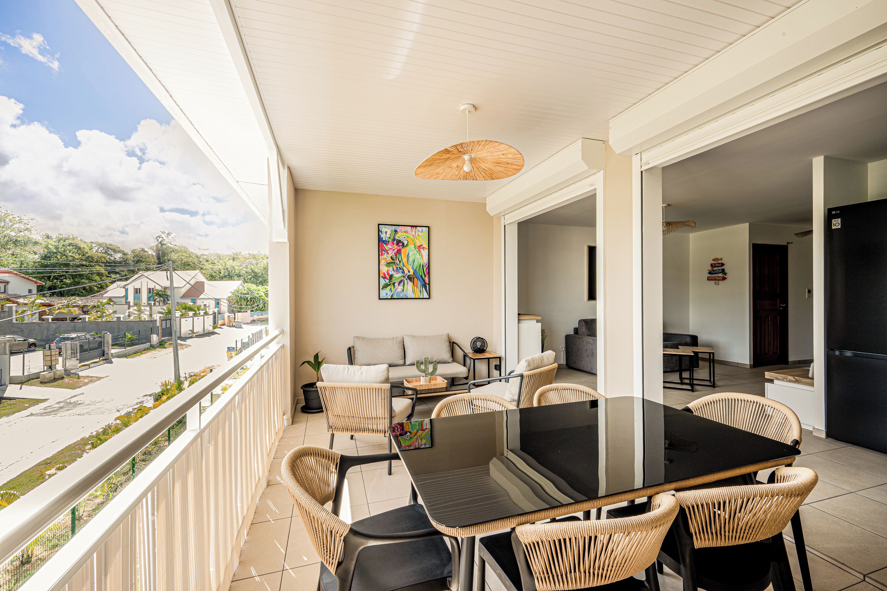 A balcony with wicker furniture, a dining table, and a painting.