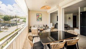 Un balcón con mobiliario de mimbre, una mesa de comedor y un cuadro.