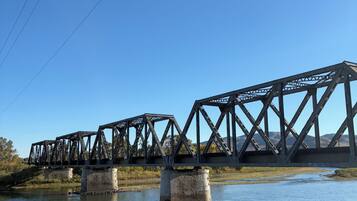 A steel bridge over a calm river with clear skies.