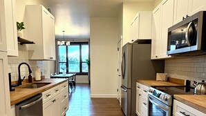Une cuisine moderne avec des meubles blancs, des appareils en acier inoxydable et un plancher en bois.