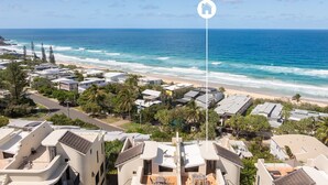Een kustwoongebied met moderne huizen, een strand en helder uitzicht op de oceaan.