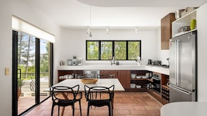 Een moderne keuken met een groot eiland, inbouwapparatuur en uitzicht door het raam.
