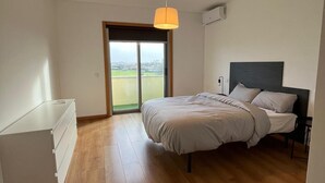 Un dormitorio con una cama, un aparador y un ventanal con vistas.