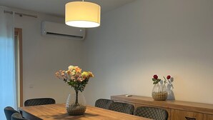 Un comedor con una mesa de madera, sillas negras, un jarrón con flores y una lámpara colgante.