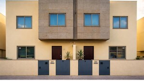 Un edificio moderno con fachada simétrica, que presenta dos puertas y ventanas centrales a cada lado.