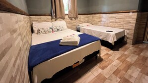 A room with two beds, a window with curtains, and a tiled floor.