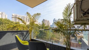 En balkon med to stole, en potteplante og udsigt over byen.
