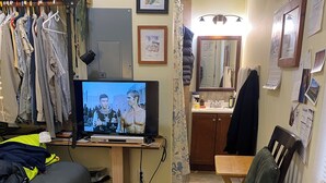 Ein gemütlicher Wohnbereich mit Fernseher, Esstisch, Sofa und Kleiderständer.
