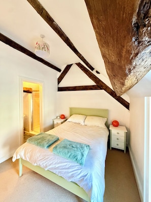 A bedroom with a bed, nightstands, and a wooden ceiling beam. - Stable Cottage – A Hidden Gem in Abergavenny Town (Abergavenny)