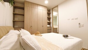 Un dormitorio con cama, armario y baño visible a través de una puerta abierta.