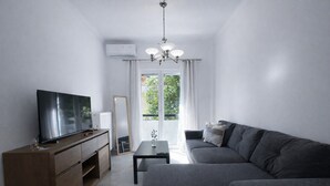 Un salon moderne avec un téléviseur à écran plat, un canapé de couleur foncée, un meuble en bois et une petite table.