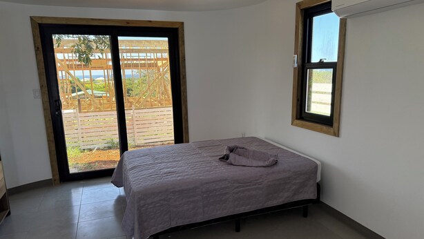 Une chambre avec un lit, une fenêtre et une porte-fenêtre coulissante donnant sur un espace extérieur.