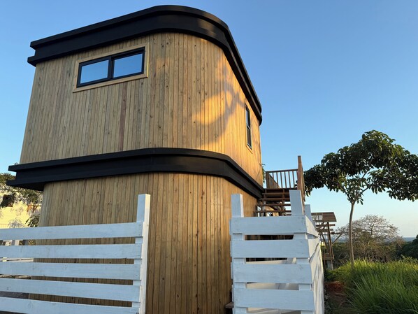 A wooden tower structure with a balcony, surrounded by a white fence.