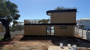 Une structure moderne en bois, dotée d’un balcon, d’une porte et d’une petite fenêtre.