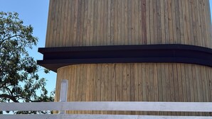 Une structure cylindrique en bois, dotée d’une fenêtre et entourée d’une clôture blanche.
