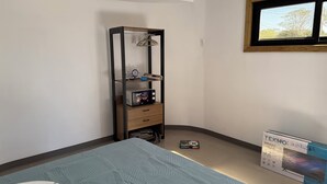 Une chambre à coucher avec un lit, une armoire, une télévision et une fenêtre.