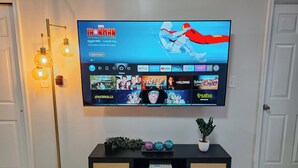 Een flatscreen-tv aan de muur met een streamingdienst interface en verschillende series en films.