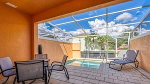 Een zonnig buitengebied met een zwembad, ligbedden en een glazen patio.