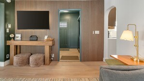 A modern living room with a wooden TV stand, ottomans, a lamp, and a sofa. - Spacious 3BR Home Near Burlington with hot tub ~ Sleeps 12 (Winooski)