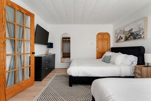 Ein Schlafzimmer mit zwei Betten, einem Holzschrank, einem Fernseher und einem Bild an der Wand.