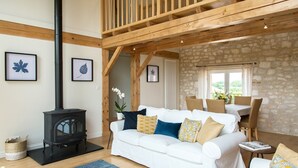 A cozy living room with a white sofa, a black wood-burning stove, and a stone wall.