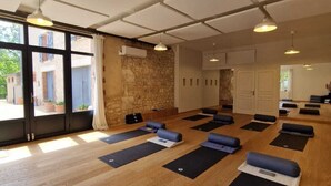 A spacious room with wooden flooring, yoga mats, and exercise balls arranged for physical activities.