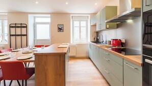 Une cuisine moderne avec un îlot central en bois, des meubles de couleur claire et un grille-pain rouge.