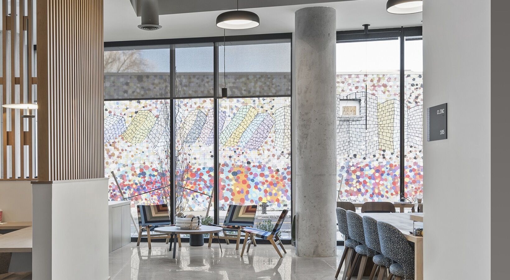 Un interior moderno con ventanas amplias, una mesa redonda con sillas y un letrero de clínica visible.
