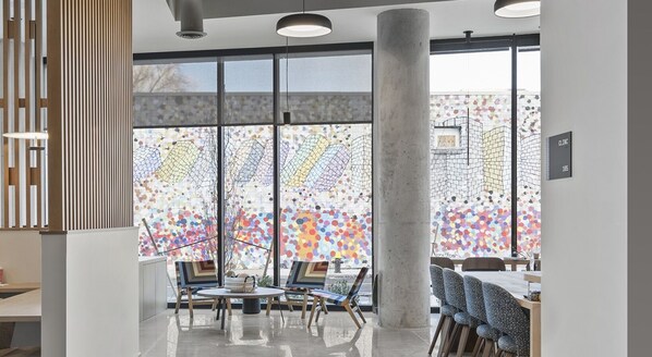 Un intérieur moderne avec de grandes fenêtres, une table ronde entourée de chaises et une enseigne de clinique bien visible.