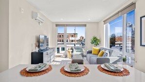 A modern apartment with a dining area, a living space, and large windows offering city views. - Elysian Residences Boston (Boston)