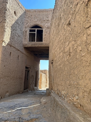 An arched doorway leading into a building with a rustic, earthen texture.
