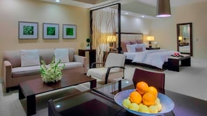 A hotel room with a sofa, a dining table with a fruit bowl, a bed, and a mirror. - King Studio Suite w/ Kitchen & Jetted Tub + Spa (Miami)