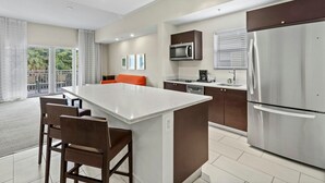 A modern kitchen with a central island, stainless steel appliances, and a dining area with wooden chairs. - 1BR Double Suite w/ ADA Features | Dining & Spa (Miami)