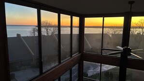 A room with large windows overlooking a body of water and a sunset. - Spacious and fully loaded 4 Bed 4 Bath with Amazing Views on Grand Lake. (Afton)