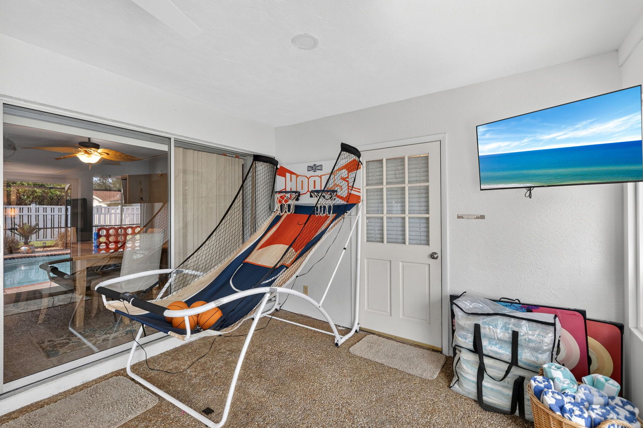A room with a hammock chair, a pool view, a television, and storage bags.
