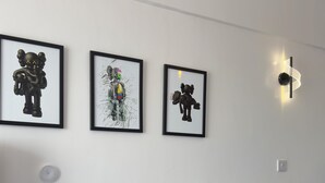 Ett modernt vardagsrum med en grå soffa, ett vitt sidobord med en bok på och tre inramade konstverk på väggen.