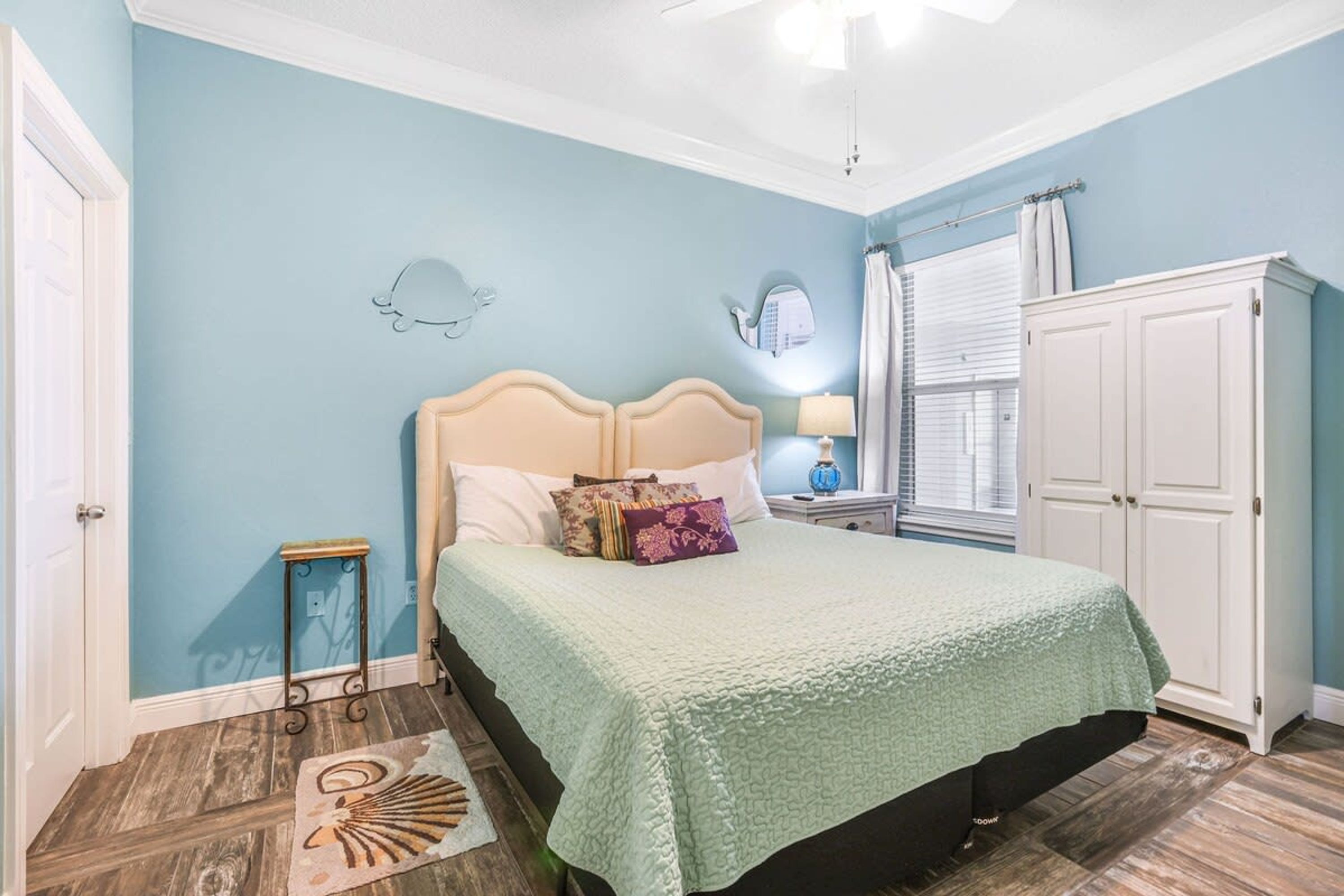 Una camera da letto con un letto, un comodino, un armadio e una finestra con tende.