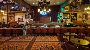 A bar area with a stage, bar stools, and a patterned carpet. - The Tonopah Station  (Tonopah)