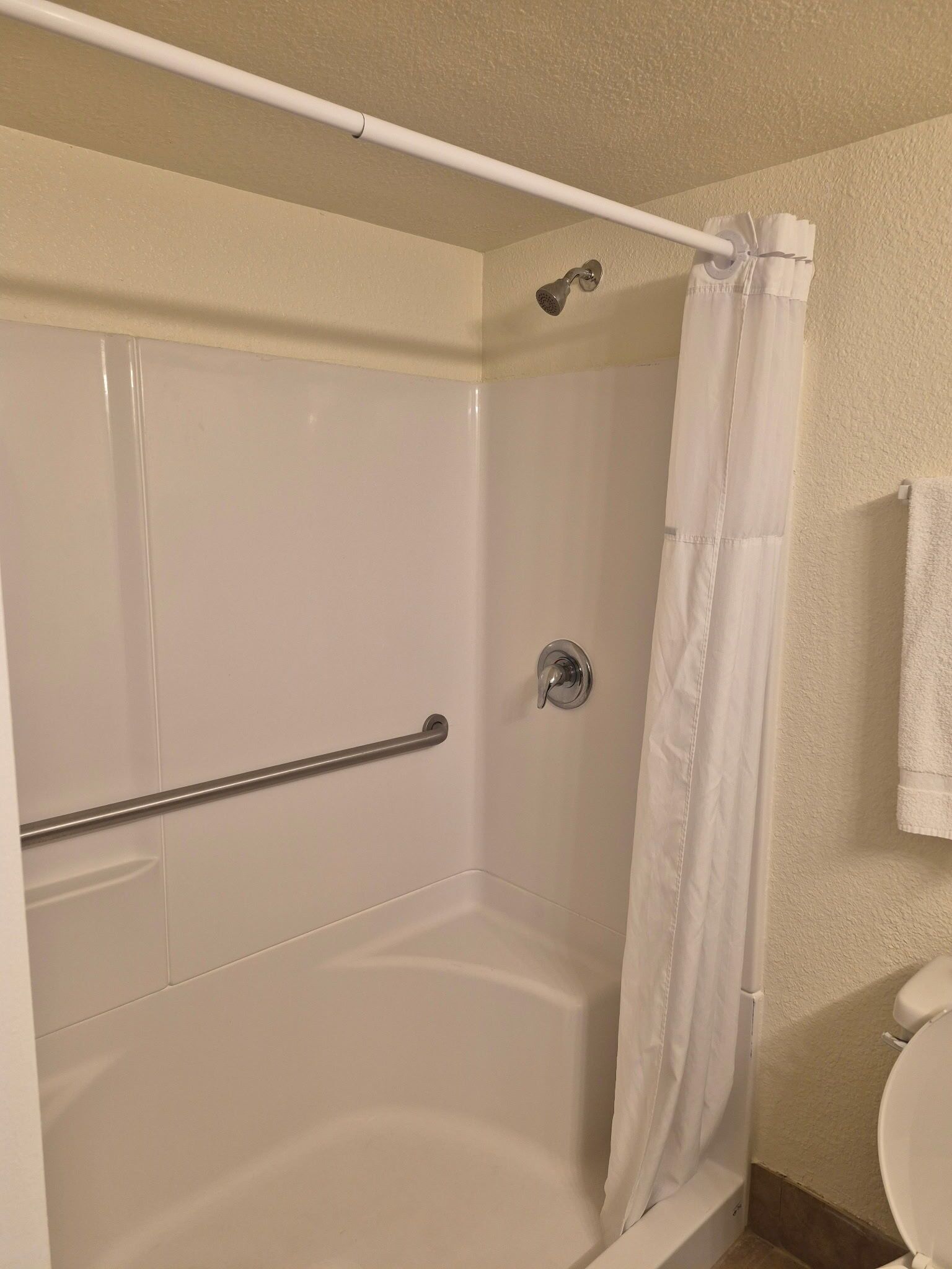 A bathroom with a shower, a toilet, and a towel rack.