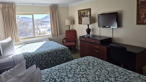 A hotel room with two beds, a desk, a chair, a TV, and a window with curtains. - The Tonopah Station  (Tonopah)